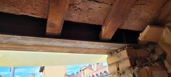 Apertura ricavata in un solaio in legno per il vano ascensore, accanto a una muratura portante esistente