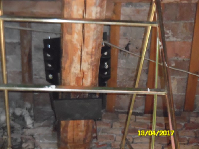 Dettaglio di staffe metalliche imbullonate su una trave in legno, durante un intervento di rinforzo strutturale