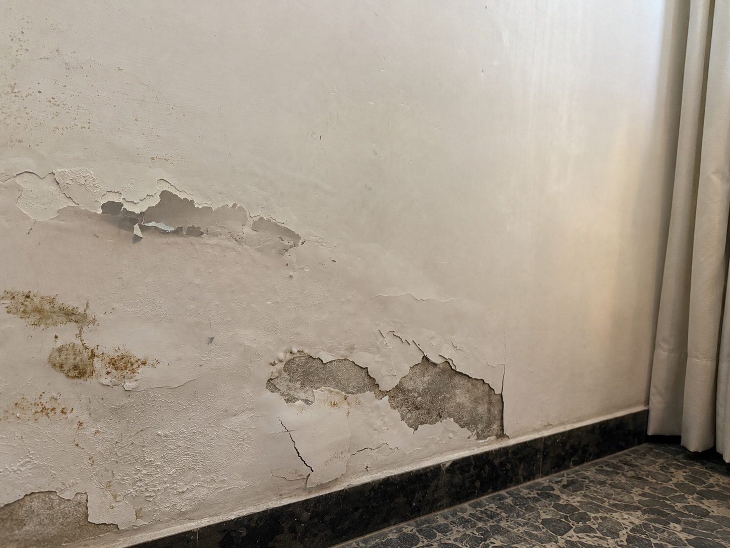 Umidità e distacco di intonaco alla base di un muro