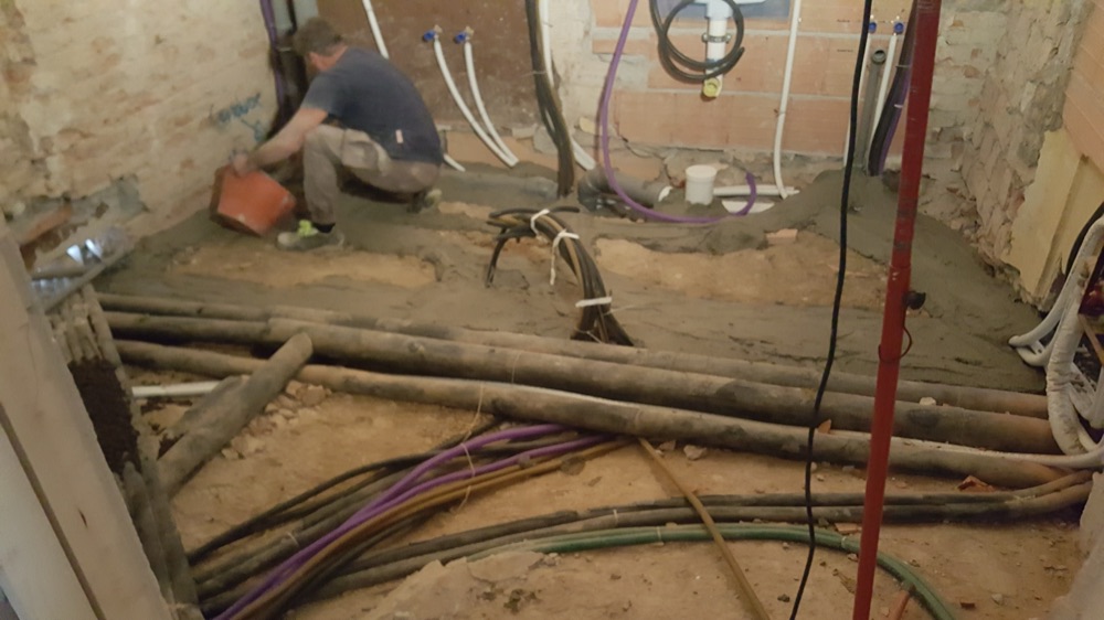 Scavo a pavimento con cavi elettrici e tubazioni idrauliche posati insieme, durante il rifacimento degli impianti