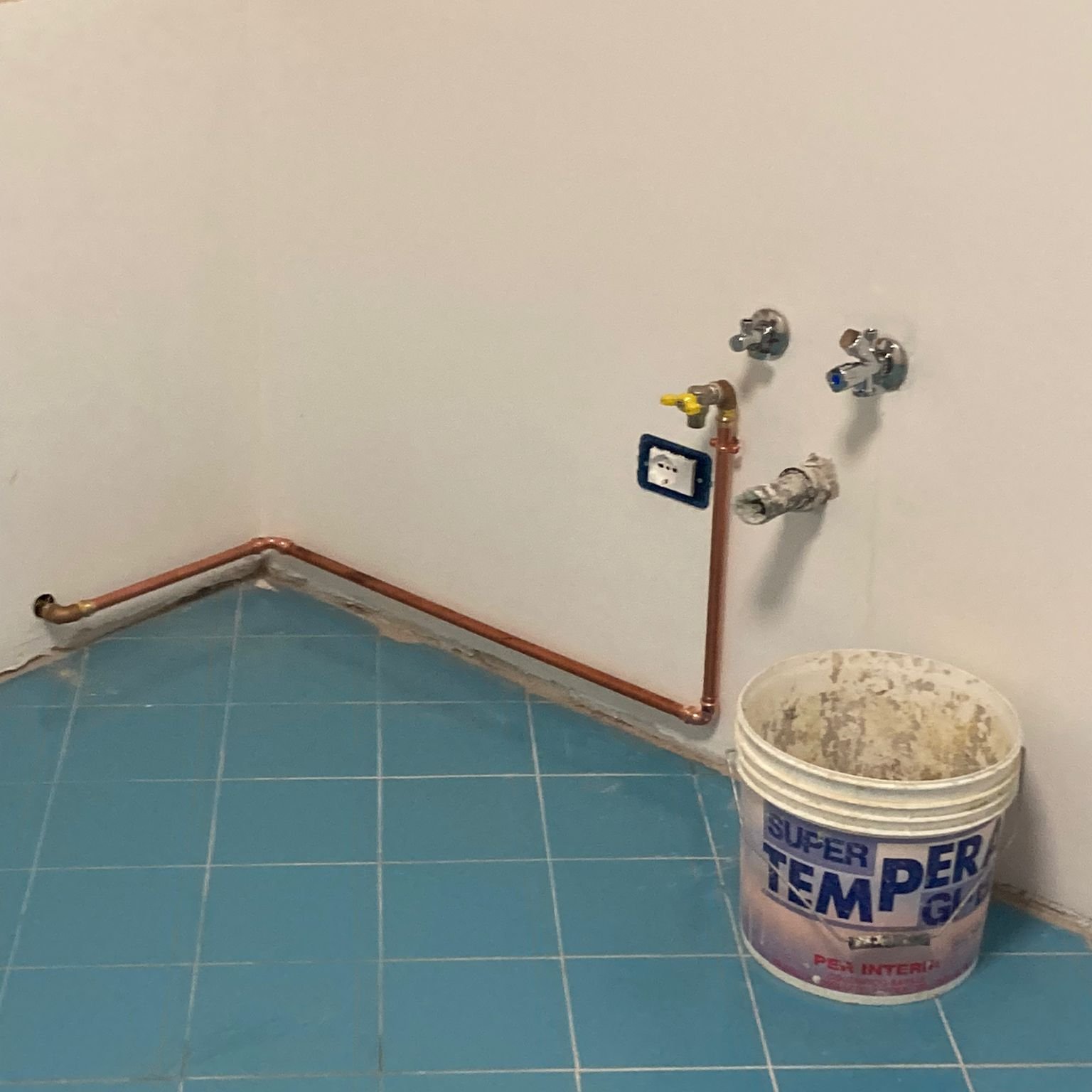 Tubo di rame dell'impianto idraulico e presa elettrica a muro in un bagno durante la ristrutturazione