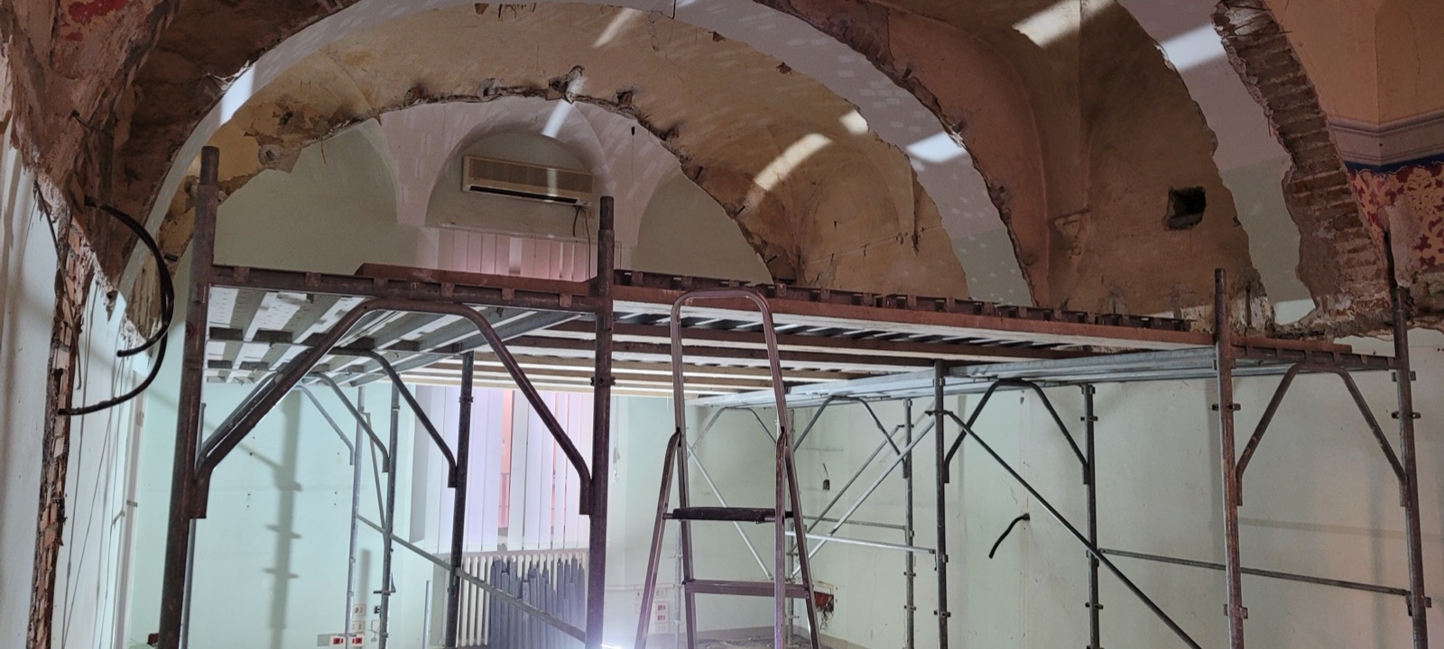 Volta a crociera in mattoni e intonaco originale messa a vista durante un restauro, con ponteggio sottostante in un edificio storico