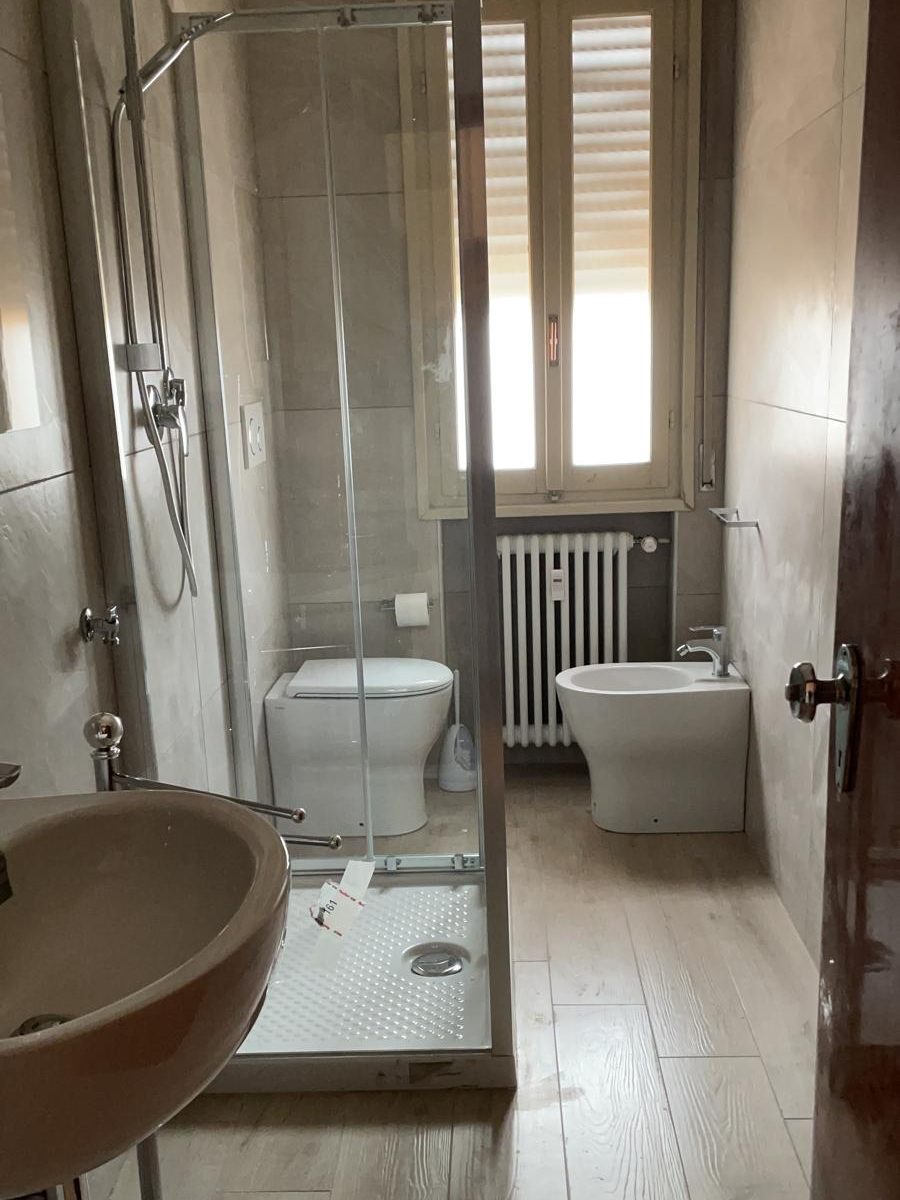 Stesso bagno dopo la ristrutturazione, con box doccia in vetro, sanitari nuovi e piastrelle moderne