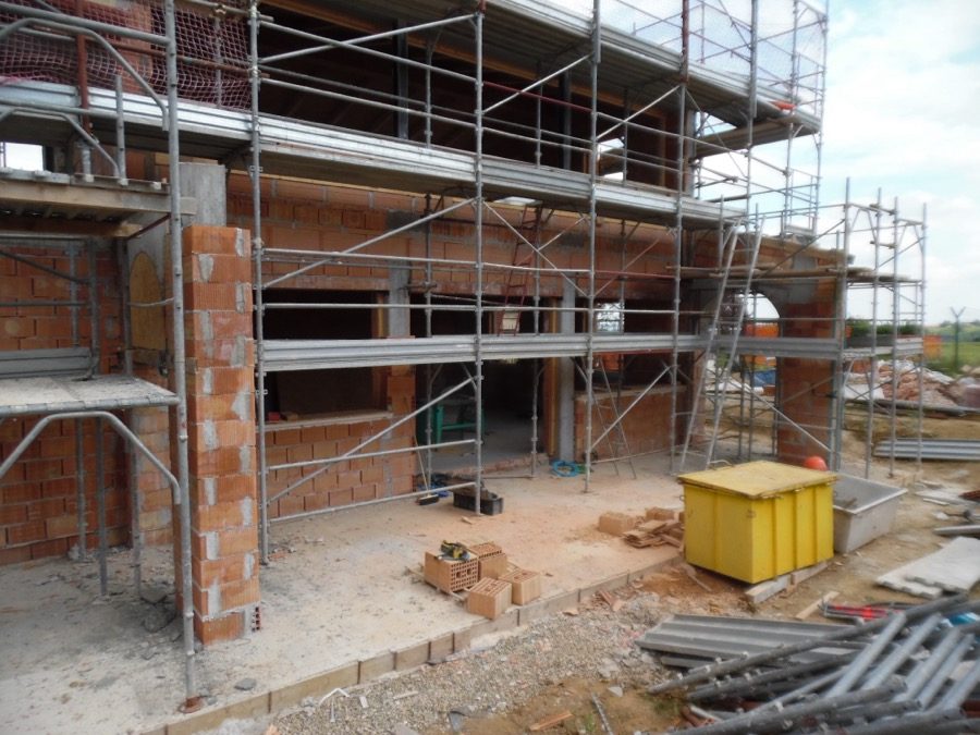 Edificio in costruzione con tamponature in laterizio, aperture e struttura del tetto